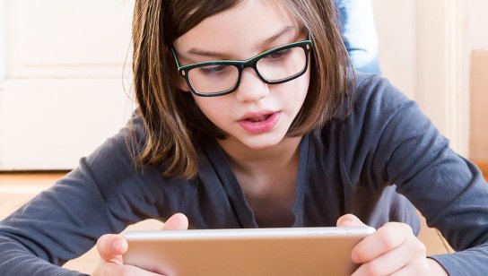Girl in glasses looking at tablet computer.